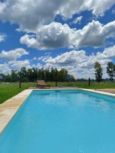 a swimming pool with a bench and a blue sky at Guidai Alojamiento in Tacuarembó