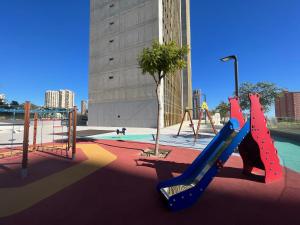 un parque infantil vacío con tobogán y columpios en Intempo Residence en Benidorm