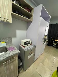 a small kitchen with a refrigerator and a sink at Iza's Alabang Studio Apartment in Manila