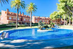 una piscina di fronte a un edificio con palme di Tamarit by Unik Tarragona a Tarragona