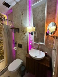 a bathroom with a toilet and a sink with purple lights at City Center Beach side Hut in Tbilisi City