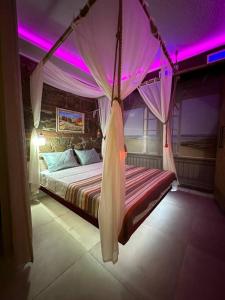 a bedroom with a canopy bed with purple lighting at City Center Beach side Hut in Tbilisi City