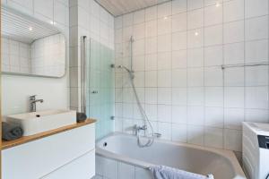 a bathroom with a bath tub and a sink at Apartment Bodman in Friedrichshafen in Friedrichshafen +10 photos