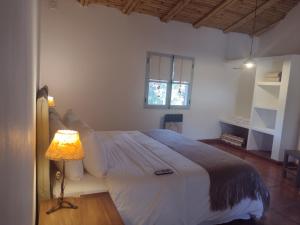 1 dormitorio con 1 cama con lámpara y ventana en Pumahuasi Hotel Boutique en Purmamarca