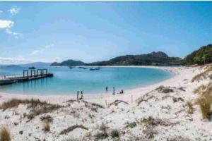a beach with a pier and people on the sand at Piso lujo en Gran Vía con garaje in Vigo