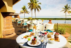 een tafel met eten op een terras met de oceaan op de achtergrond bij Taj Fort Aguada Resort & Spa, Goa in Candolim