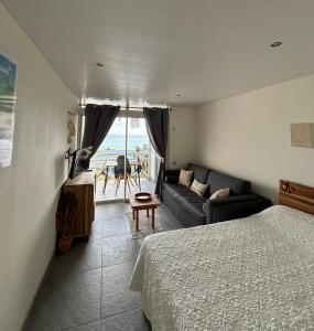 a bedroom with a bed and a couch and a television at Bohème créole in Le Diamant +22 photos