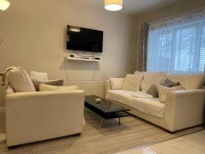 un soggiorno con 2 divani bianchi e una TV di Letterkenny Three Bedroom Town Centre Apartment a Letterkenny