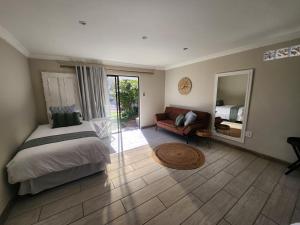 a bedroom with a bed and a couch and a mirror at On Enslin selfcatering in Middelburg +24 photos