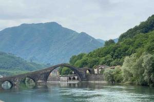 a bridge over a river with mountains in the background at THE REAL TUSCANY in Casabasciana