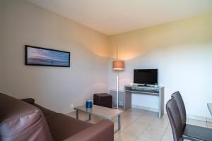 Les Thermes 421- Appt pour 4 avec piscine partagée في كونكارنو: غرفة معيشة مع أريكة وطاولة مع تلفزيون