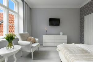 a bedroom with a bed and a chair and a tv at Elite Apartments Mariacka Premium in Gdańsk