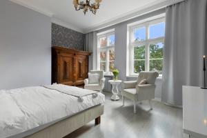a bedroom with a bed and two chairs and windows at Elite Apartments Mariacka Premium in Gdańsk
