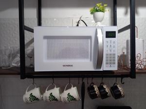 eine Mikrowelle auf einem Regal mit Tassen und Tassen in der Unterkunft Lindo Apartamento na Frei Caneca in São Paulo