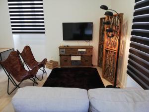 uma sala de estar com um sofá e uma televisão e cadeiras em Azores Calheta Inn T2 Frente Boa Nova em Ponta Delgada