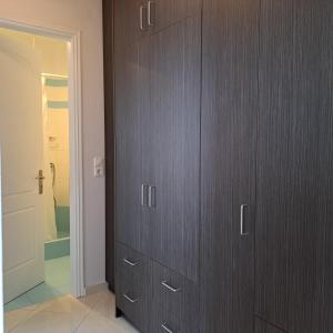 a closet with wooden cabinets in a bathroom at Ithaca in Perdika