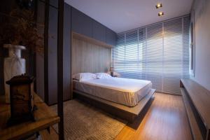 a bedroom with a bed and a large window at Studio 204 Parque Una com garagem in Pelotas