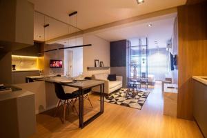 a kitchen and living room with a table and a couch at Studio 204 Parque Una com garagem in Pelotas