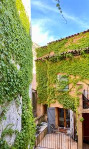 a building covered in green ivy with a balcony at Appart'Terracotta - Au cœur de Lorgues in Lorgues