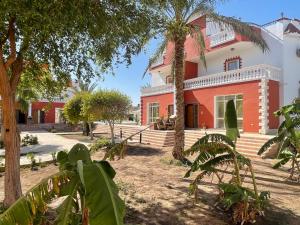 un edificio rojo y blanco con palmeras delante en Moubark 6 Villa 6 en Hurghada