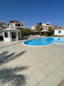 赫尔格达Hurghada-Magawish Villa 6的一座带椅子的游泳池和一座毗邻大楼的凉亭