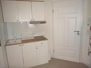 a kitchen with white cabinets and a white door at Villa Rosali Boutique Hotel in Hamburg