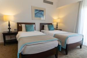 a hotel room with two beds and two lamps at Arkin Palm Beach Hotel in Famagusta