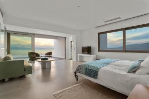 um quarto com uma cama grande e uma sala de estar em Villa Artemis - New Magnificent Beachfront Villa with Infinity Pool! em Kranidi