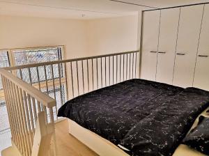 a bedroom with a bed with a black blanket at Loft next to train station & close to airport in Vantaa