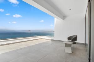 a white room with a chair and a large window at Villa Artemis - New Magnificent Beachfront Villa with Infinity Pool! in Kranidi +37 photos