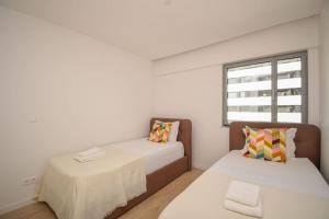 1 dormitorio con 2 camas, mesa y ventana en Stylish Apartment near the Airport, en Lisboa