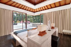 a bedroom with a bed with a desk and a window at Endless Memories for Large Groups in Private Jungle Retreat in Tanah Lot