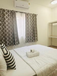 a white bed with two rolled towels on it at The Chill Town Home in Maha Sarakham