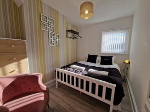 1 dormitorio pequeño con 1 cama y 1 silla en Comfortable 3 Bed home Merthyr Tydfil near Bike Park Wales & Brecon Beacons, en Dowlais