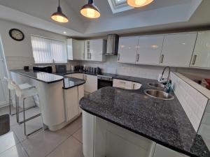 a kitchen with white cabinets and black counter tops at Comfortable 3 Bed home Merthyr Tydfil near Bike Park Wales & Brecon Beacons in Dowlais