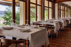 uma sala de jantar com mesas, cadeiras e janelas em Hotel & Spa El Mirador de Ulzama em Urrizola-Galáin