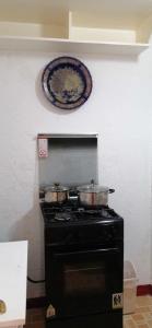 une cuisinière avec deux casseroles et une plaque murale dans l'établissement 2-storey house san pedro laguna belinda condotel 3, à San Pedro