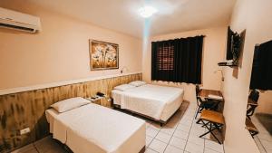 a hospital room with two beds and a television at Hotel Concord in Campo Grande