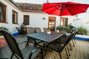 Levandulová chalupa في Vrbice: طاولة وكراسي مع مظلة حمراء على الفناء