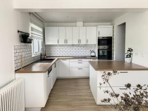 a kitchen with white cabinets and a wooden floor at L'Ulmeusienne contemporaine in Le Meux