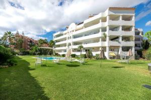 um grande edifício branco com cadeiras e uma piscina em HomeForGuest beach apartment in Puerto Banus Marbella em Marbella