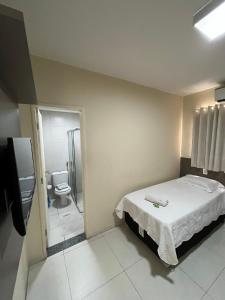 ein Schlafzimmer mit einem Bett und ein Badezimmer mit einem WC in der Unterkunft SD Plaza Hotel in Sobral
