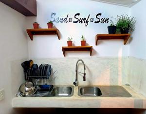 a kitchen sink with a sign on the wall at Casa do Índico in Praia do Tofo