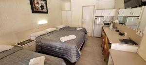 a hotel room with two beds and a kitchen at Benaraby Hilltop MotorInn in Benaraby