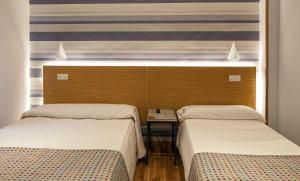 una habitación con 2 camas y una mesa entre ellas en Hostal Bezana, en Burgos 14 fotos más
