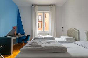 una camera con 3 letti, una scrivania e una finestra di Everyday Apartments Corte Petroni a Bologna