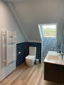 La salle de bains est pourvue de toilettes, d'un lavabo et d'une fenêtre. dans l'établissement Les Herbes Flottantes, à Englesqueville-en-Auge