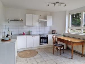 eine Küche mit weißen Schränken und einem Holztisch in der Unterkunft Ferienwohnung Waldblick in Heiligenzell