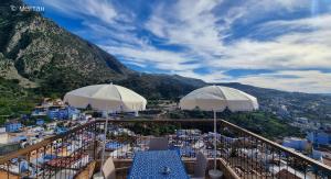 a balcony with white umbrellas and a view of a city at Casa Meftah Blue in Chefchaouen