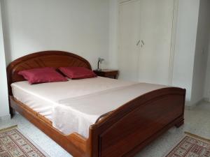 1 dormitorio con cama de madera y 2 almohadas rojas en Joli studio, 17 Avenue Hedi Nouira Ennasr 2, Ariana, Tunis, en Ariana